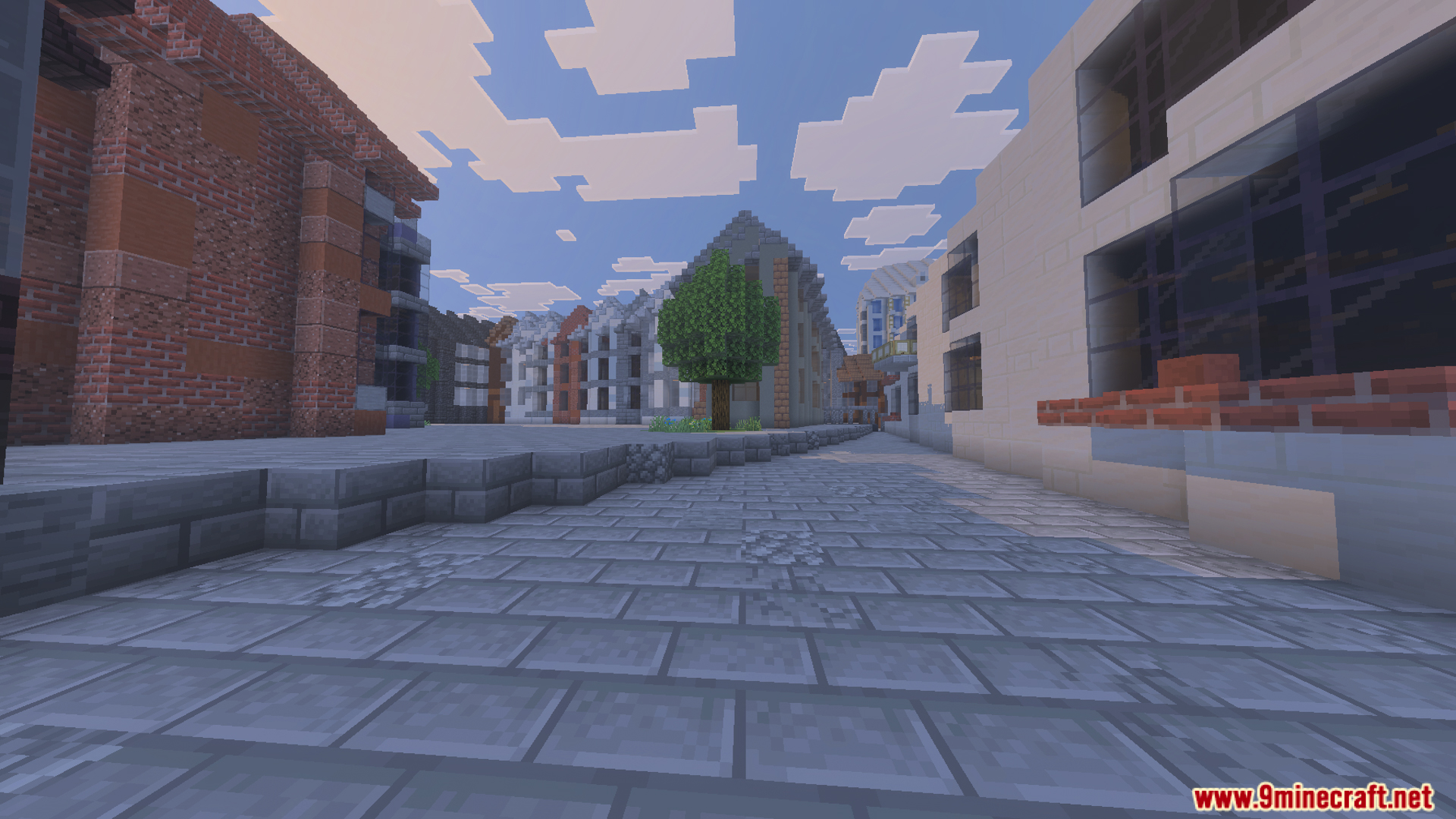 A cobblestone street with a single tree surrounded by various city buildings