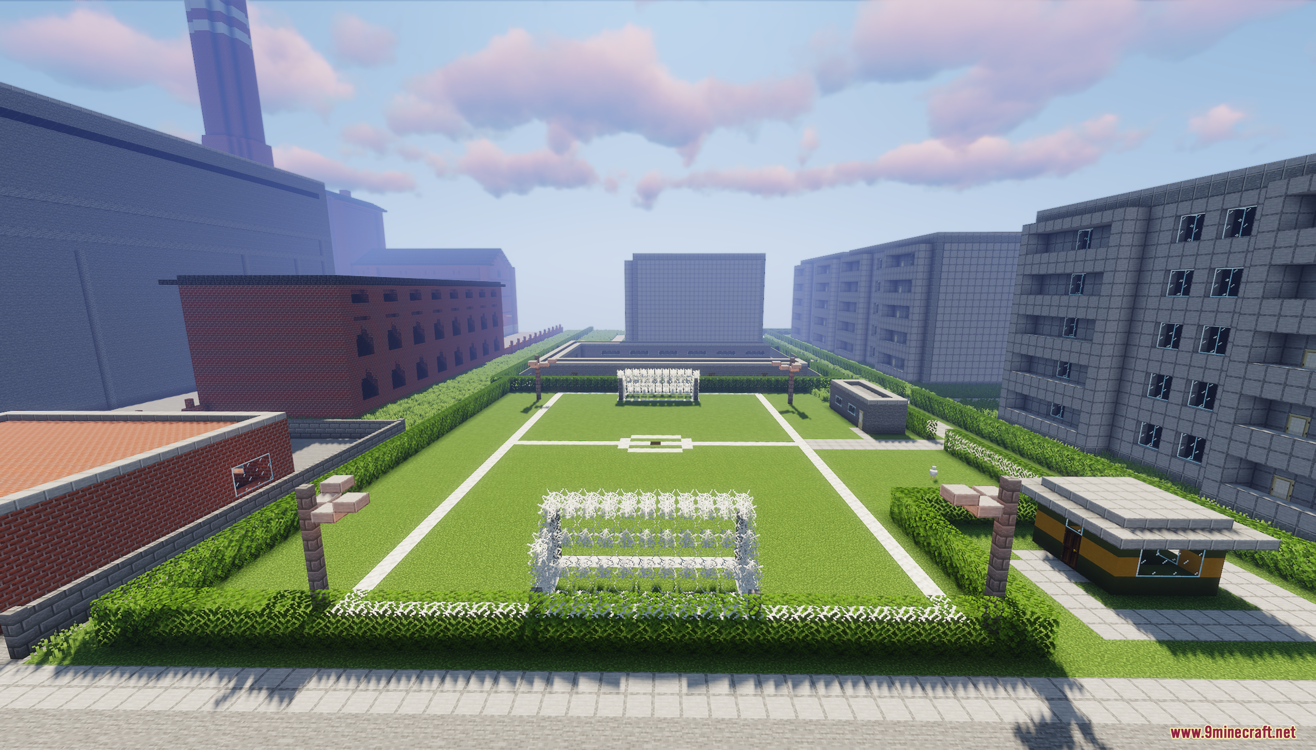 A green soccer field surrounded by apartment buildings in a Minecraft city