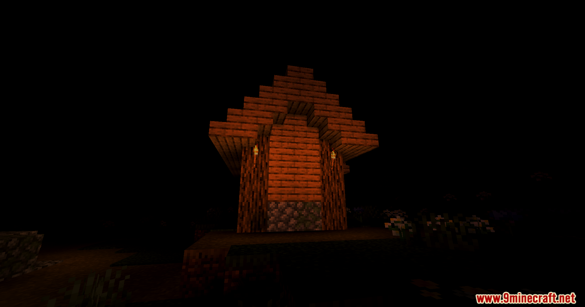 A wooden structure is dimly lit by torches in a pitch black environment