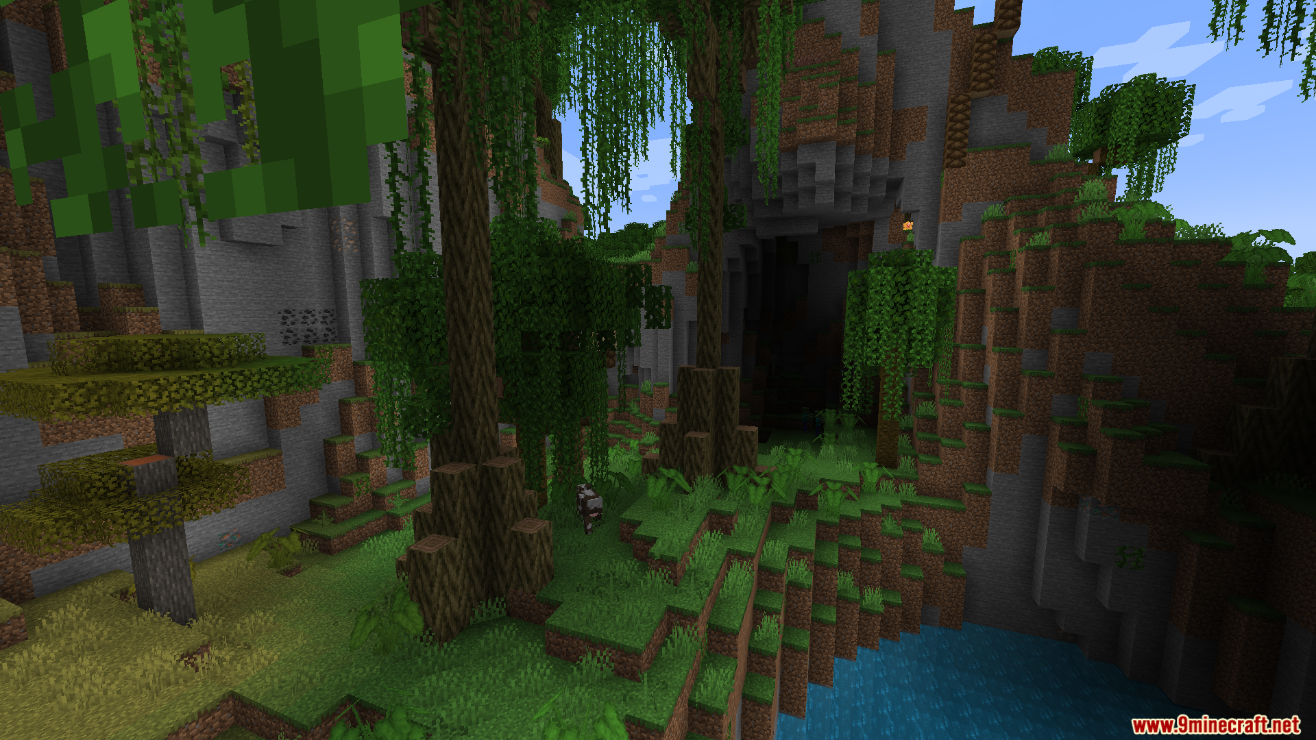 Macaws Regions Unexplored Mod Screenshot 2 A lush Minecraft biome featuring tall trees and a dark cave entrance