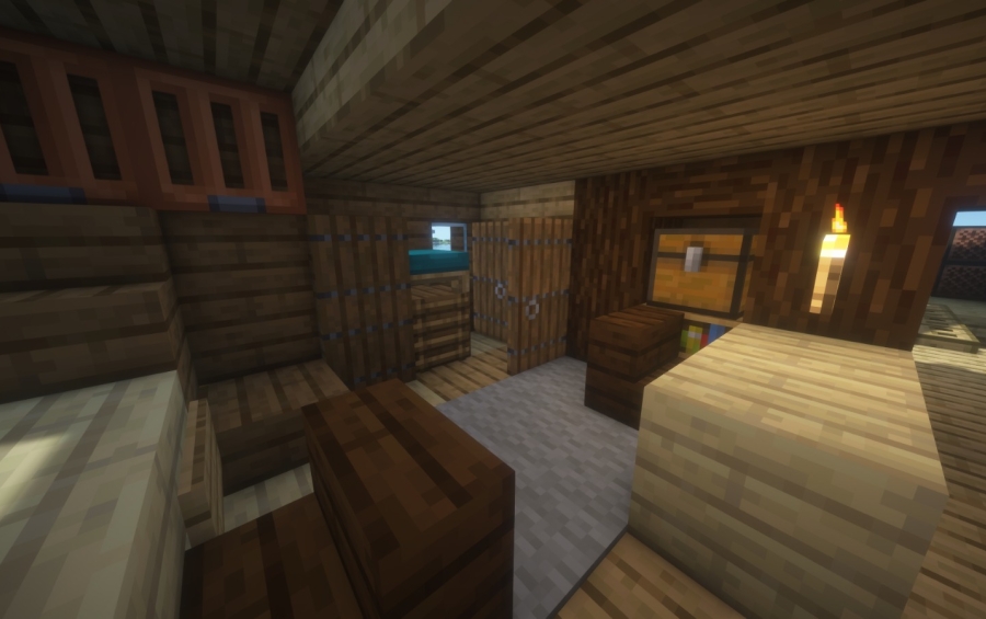 Interior view of a wooden ship cabin with a bed and chests