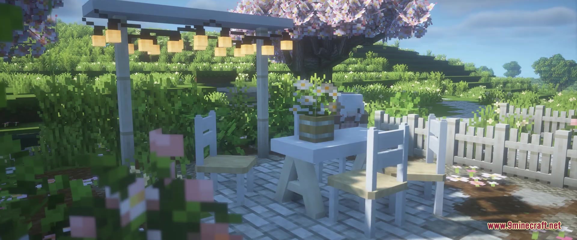 Outdoor seating area with white furniture and string lights under a cherry tree