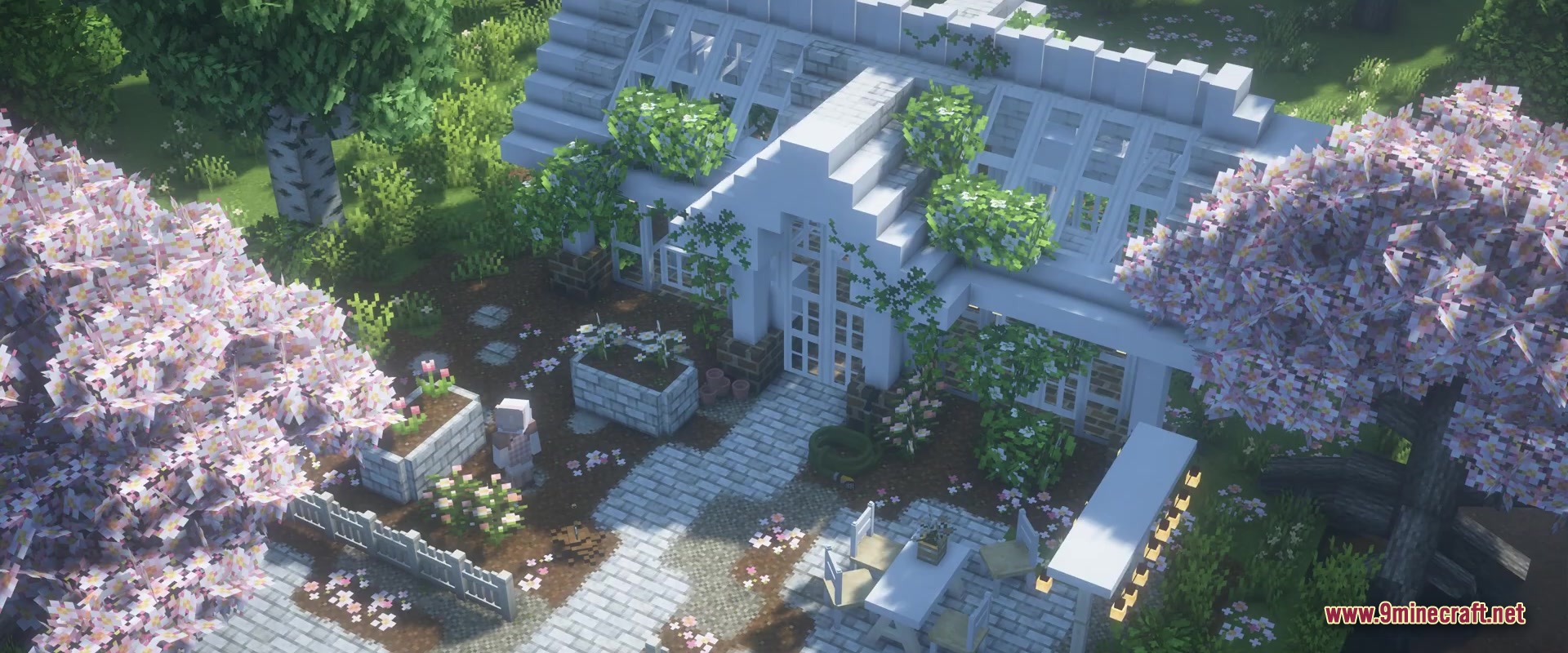 A white greenhouse surrounded by cherry blossom trees and stone paths in a garden