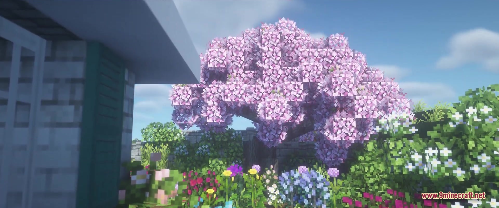 A large pink flowering tree stands in a lush colorful Minecraft garden