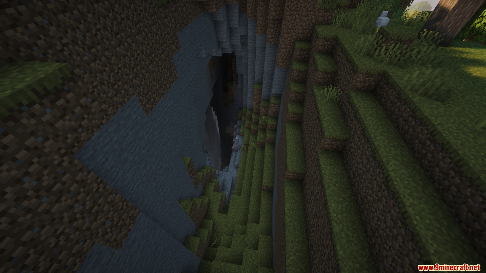 Monocle Mod Screenshot 7 A deep dark ravine opening surrounded by grass and stone blocks in Minecraft
