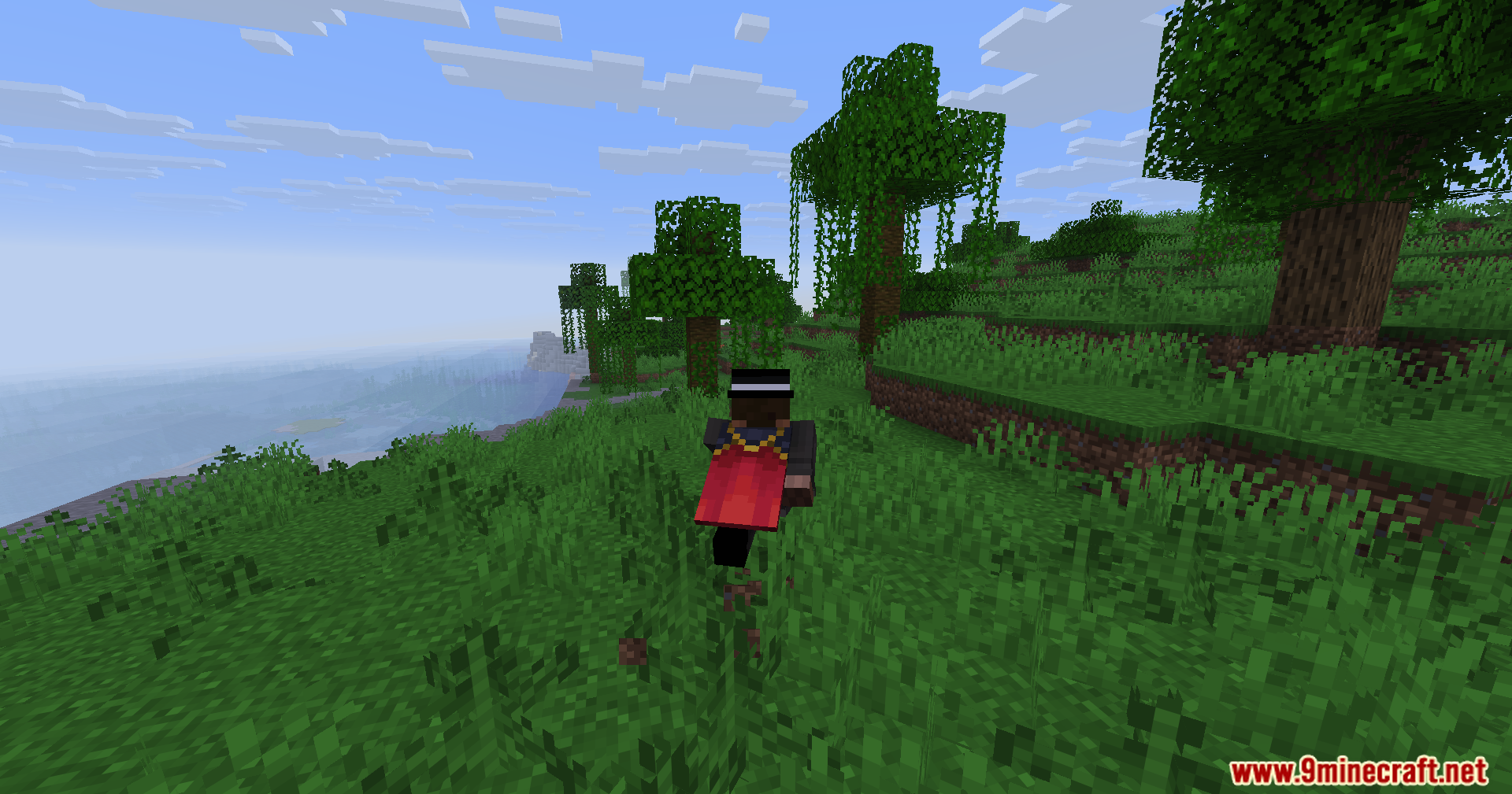 A Minecraft character with a red cape walks through a lush green forest
