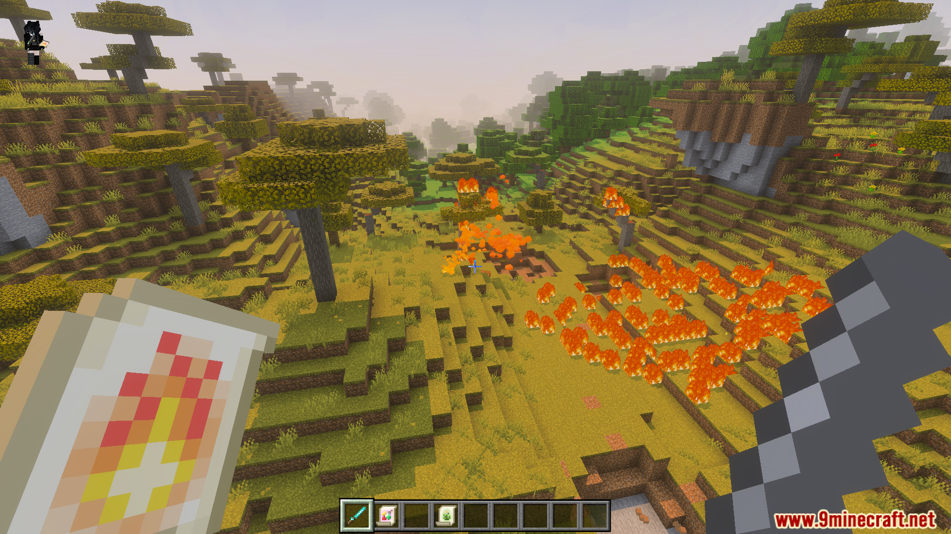 Nicos Magic Spells Addon Screenshot 7 Player holding a fire scroll while standing in a burning savanna biome