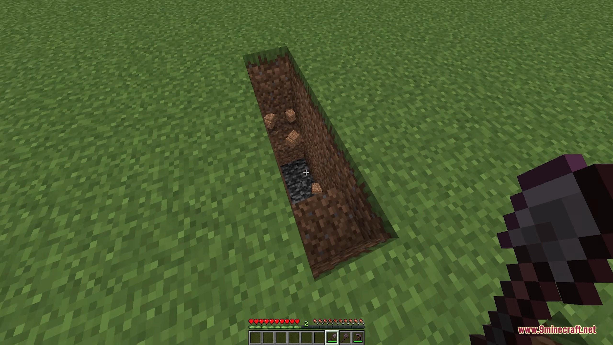 A player looks down into a deep hole reaching bedrock with a shovel