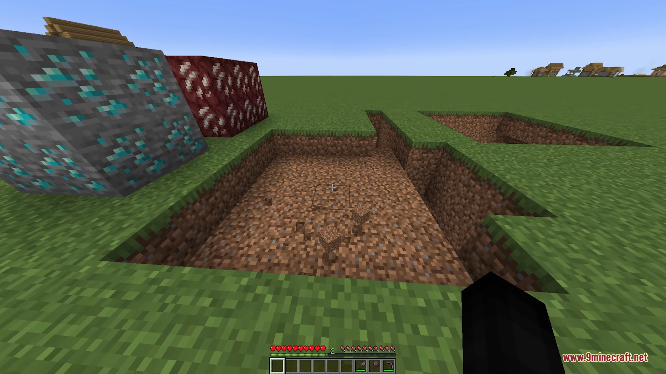 A player stands next to a large excavated pit and ore blocks