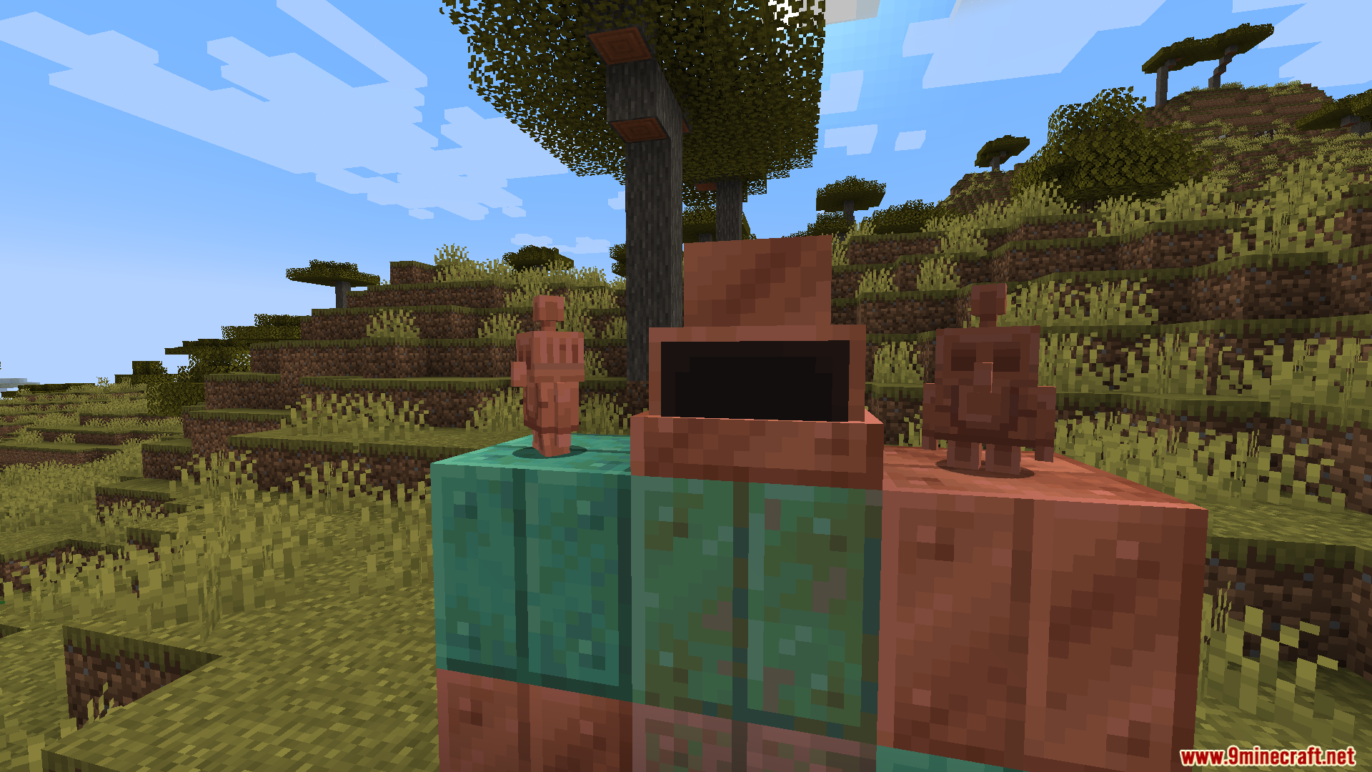 Copper statues and blocks from the Oxidized mod displayed in a savanna