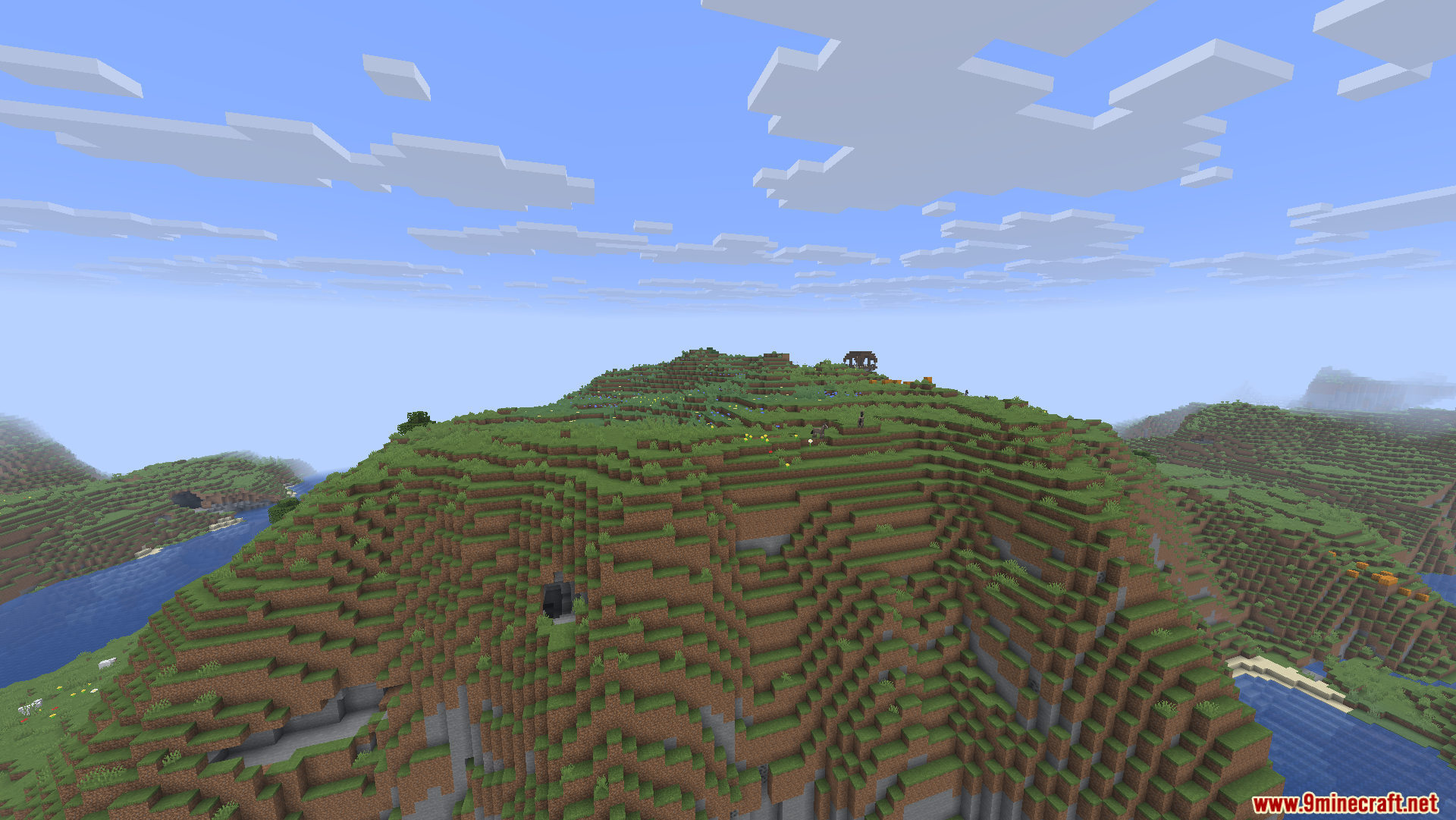 A large grassy mountain landscape with a small structure on the peak