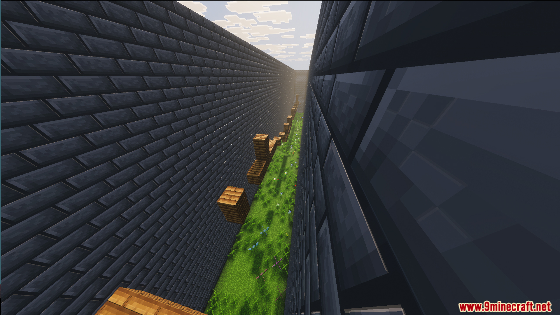 Easy parkour jumps inside a narrow stone brick corridor with grass below