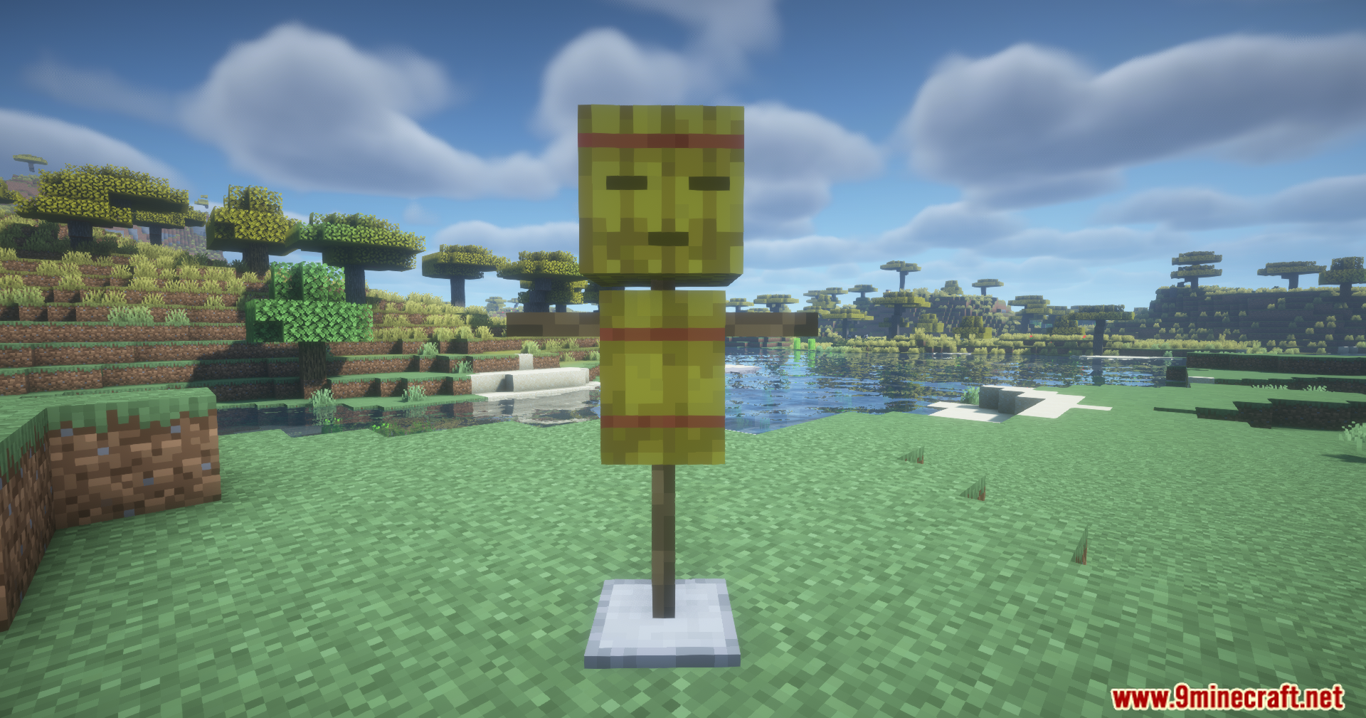 A straw training dummy standing on a stone base in a grassy field