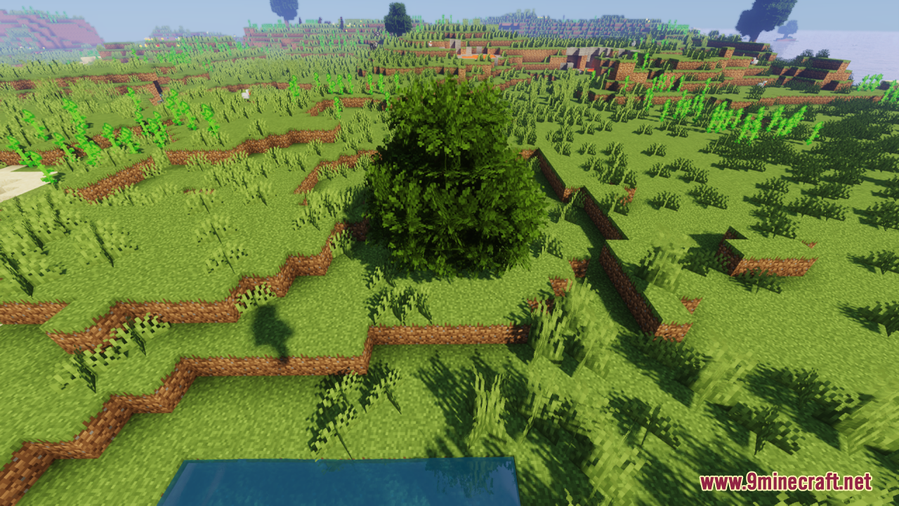 Rainbow's Foliage Resource Pack Screenshot 2 A lush green tree with bushy foliage grows on a grassy hill near water
