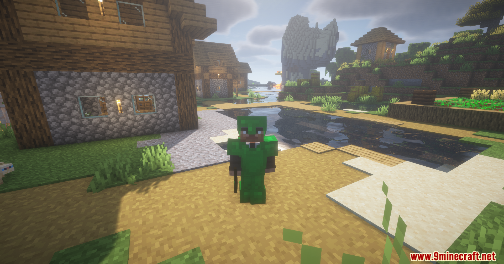 Silent Gear Metalworks Mod Screenshot 10 A player wearing green metal armor stands in a village next to water