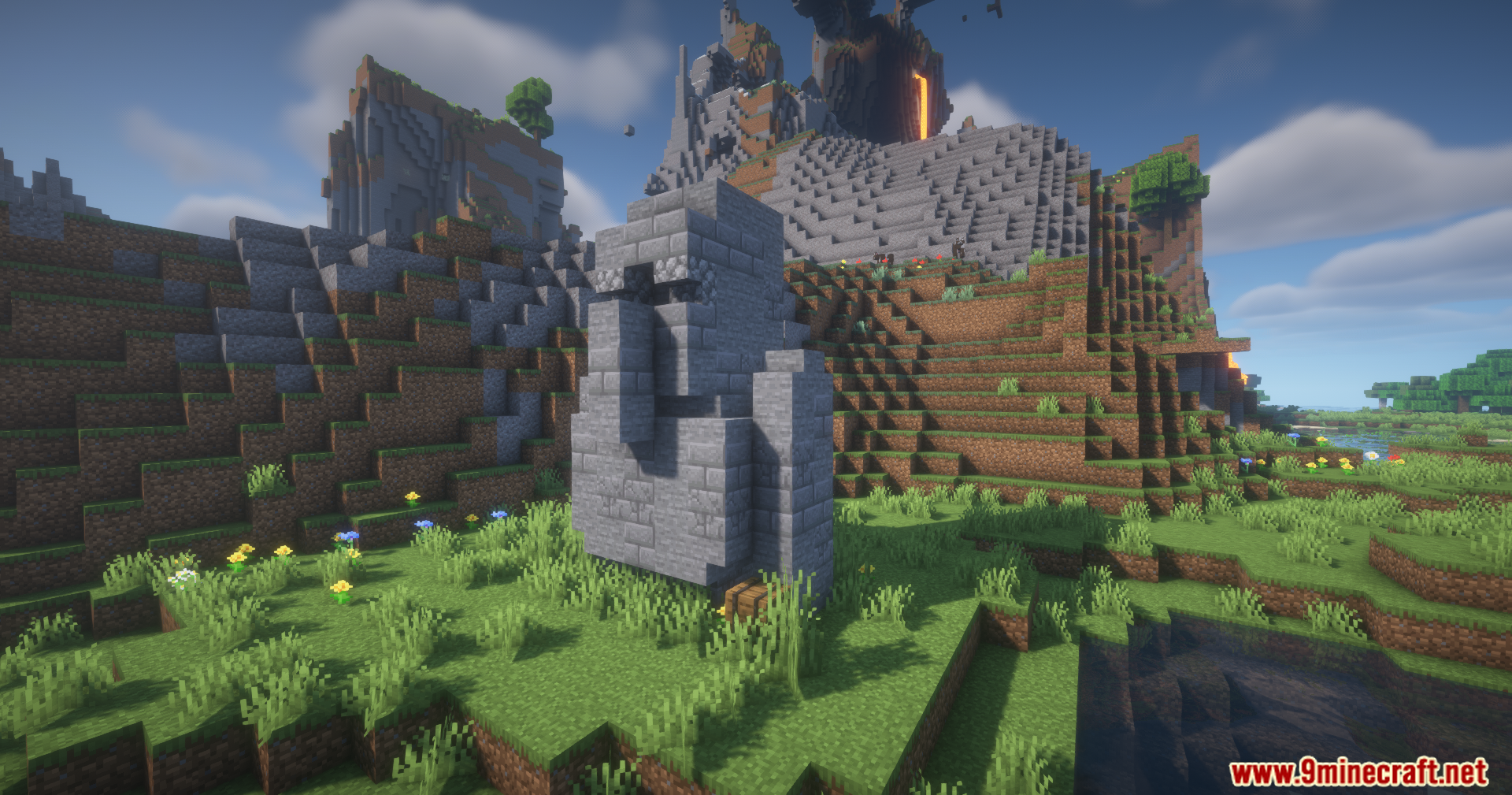 A giant stone villager statue standing in a grassy mountain landscape
