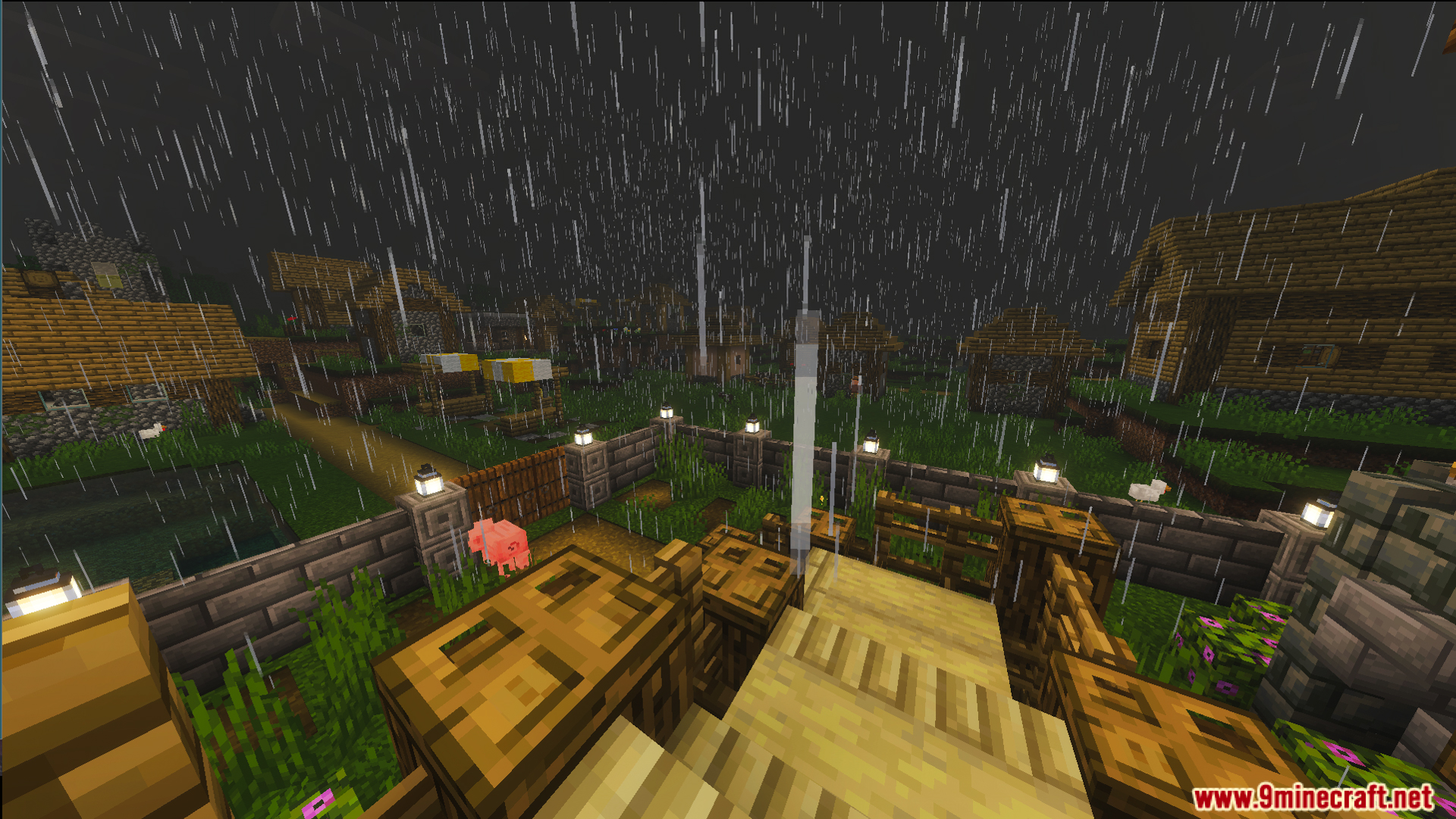 Rainy exterior view of a fenced farm and a village in the distance