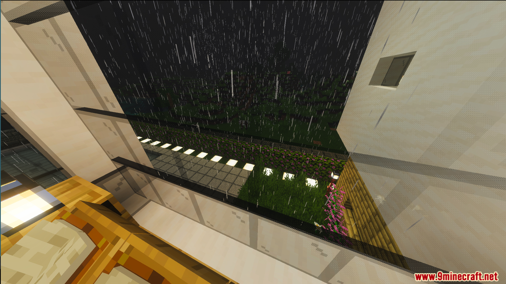 Rain falls outside a modern house balcony overlooking a garden with bright lights