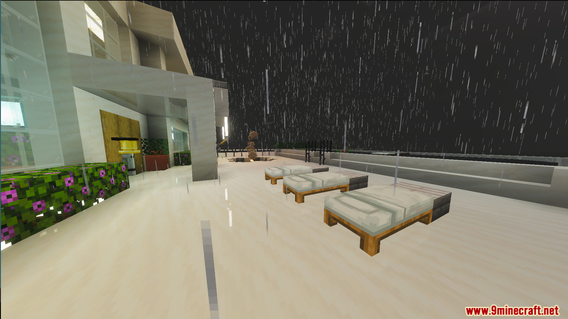 Outdoor terrace with white beds and glass railings during a rainy night