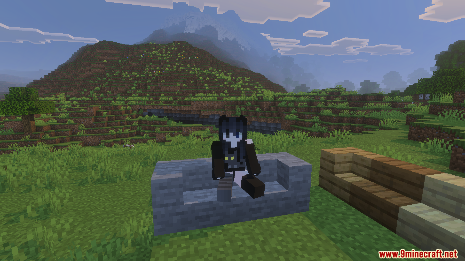 Minecraft player sitting on a stone slab bench with mountains in the background