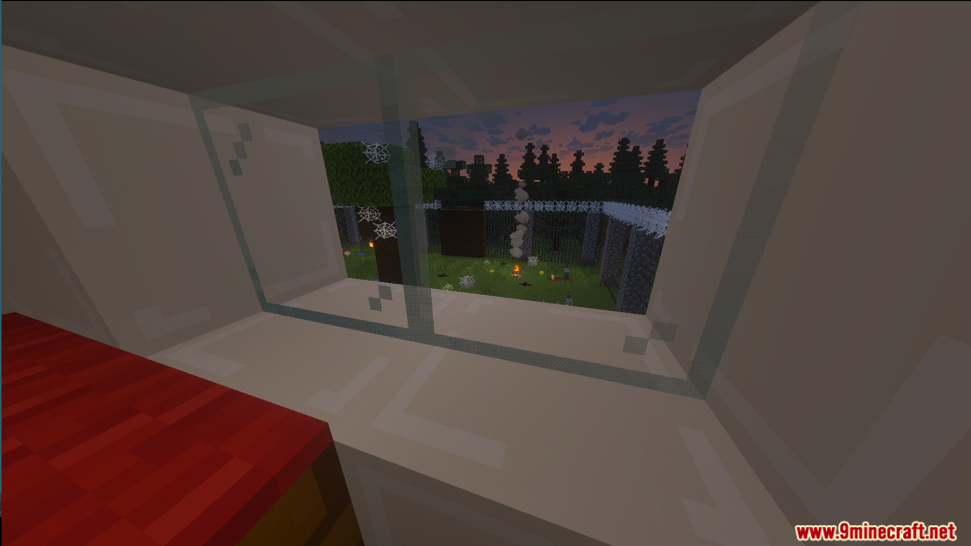 Looking through a window at a yard with cobwebs and a campfire