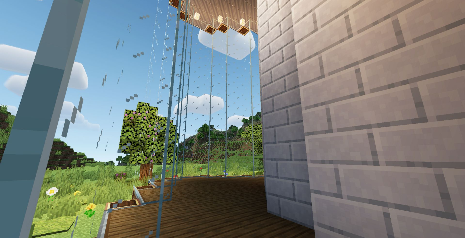 A modern balcony with glass panes and white brick walls overlooking hills