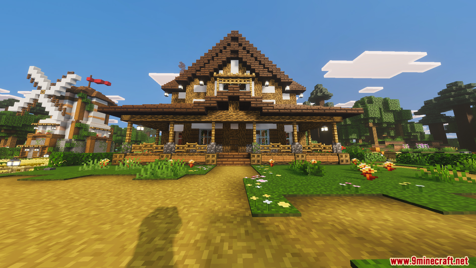 Front view of a large wooden farmhouse with a nearby windmill