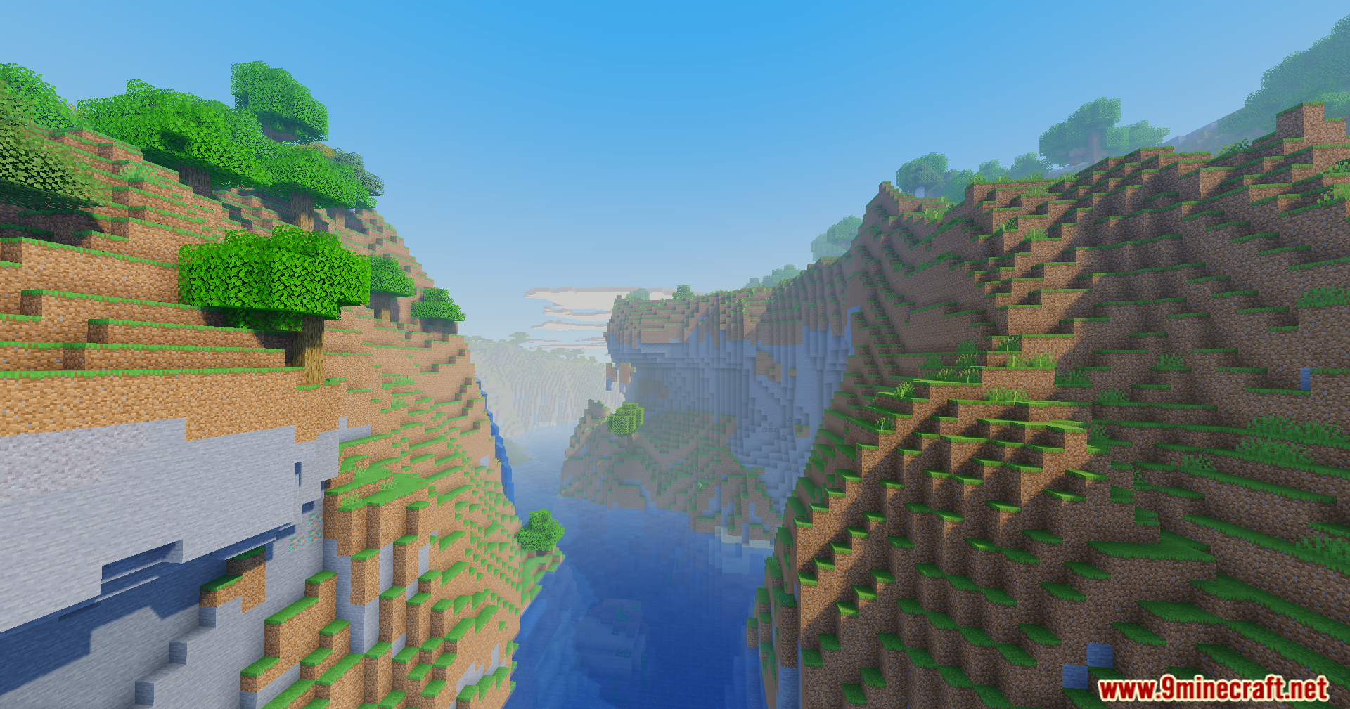 Scenic river valley between steep grassy hills under a clear blue sky
