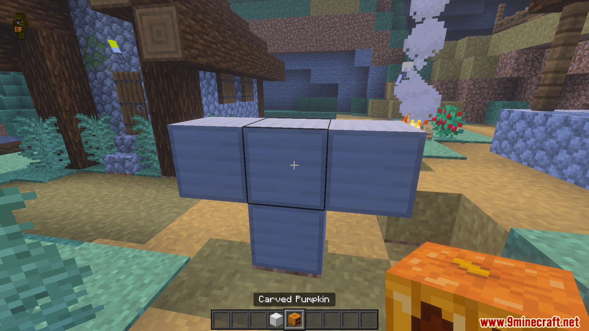 Player holds a carved pumpkin while looking at a blue block structure