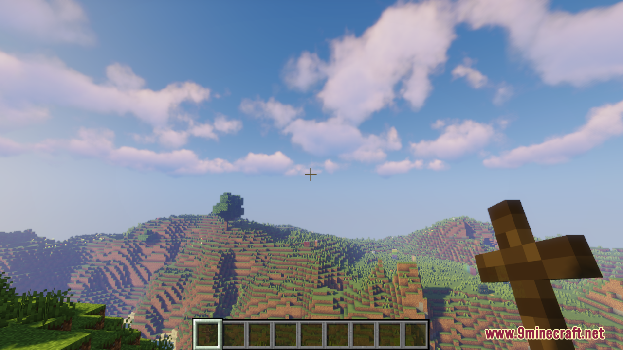 Wood Totem Cross Resource Pack Screenshot 6 A player holds a wooden cross item while looking at the Minecraft world