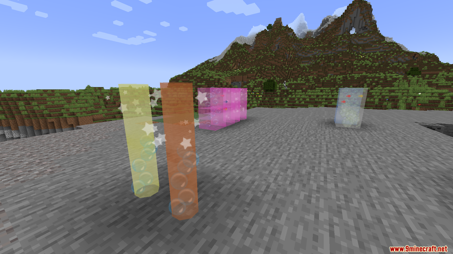 Tall tinted glass cylinders containing moving particle effects against a mountain backdrop