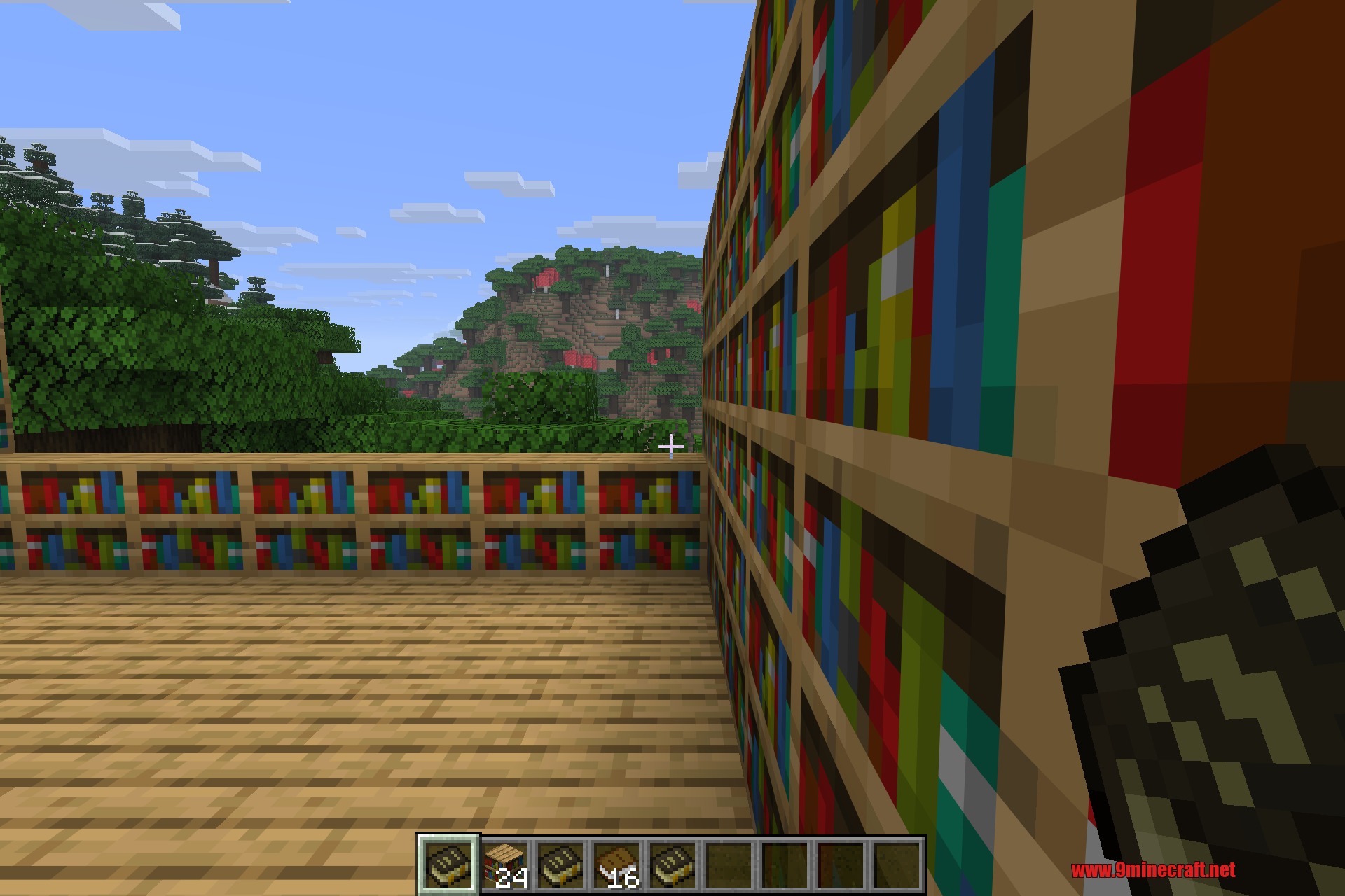 Akashic Tome 9minecraft Mod Screenshot 5 Player holding the Akashic Tome while standing near a wall of bookshelves