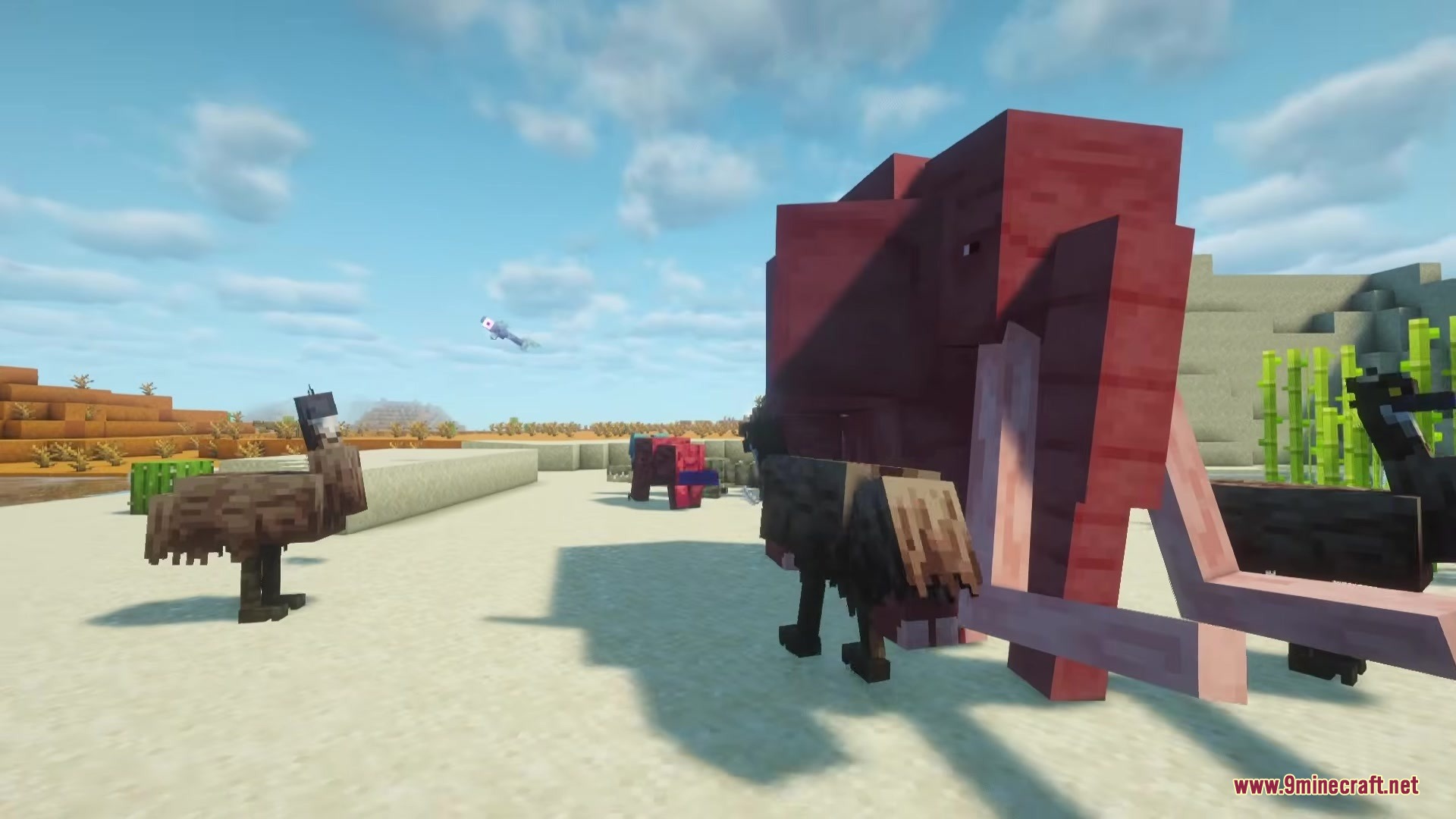 A reddish mammoth and an emu stand on a sandy plain