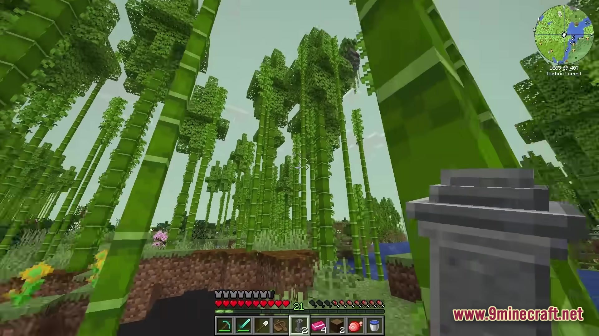 A player explores a dense bamboo forest biome while holding a decorative stone pillar item