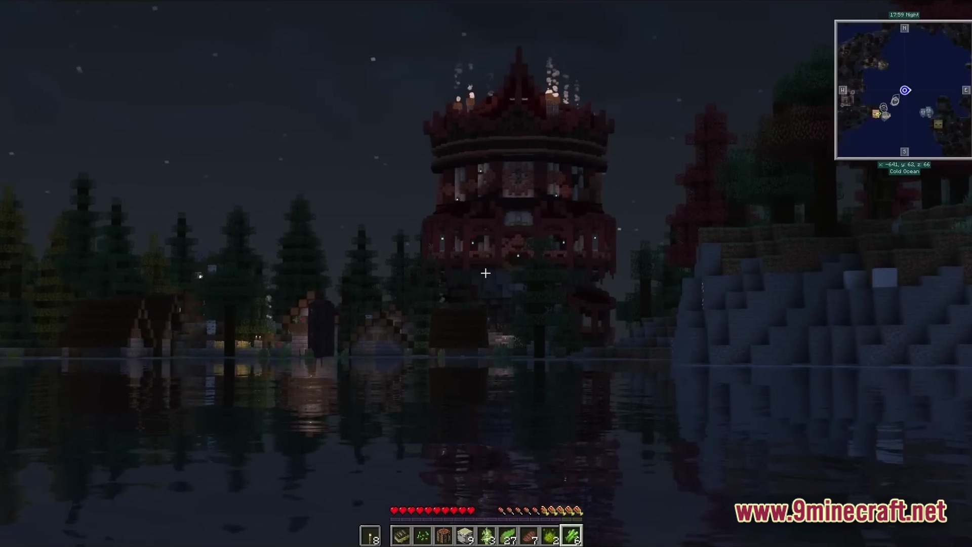 A large red circular tower structure stands beside a lake at night in a forested biome