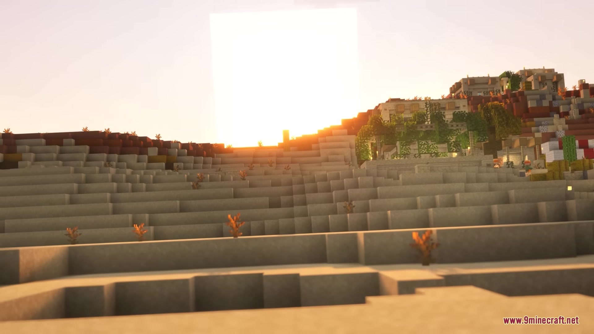 The sun sets over a desert landscape featuring ancient stone ruins