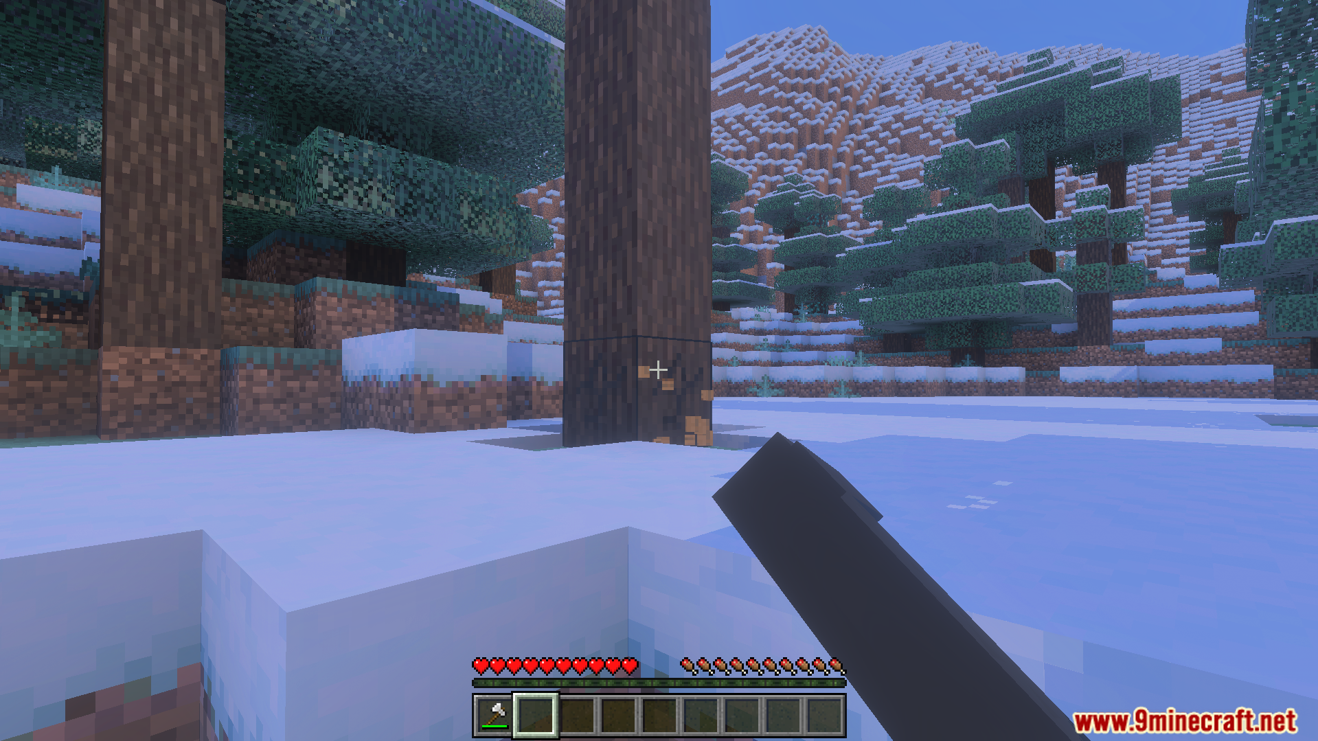 Player uses an axe to chop a tall spruce tree in snowy terrain