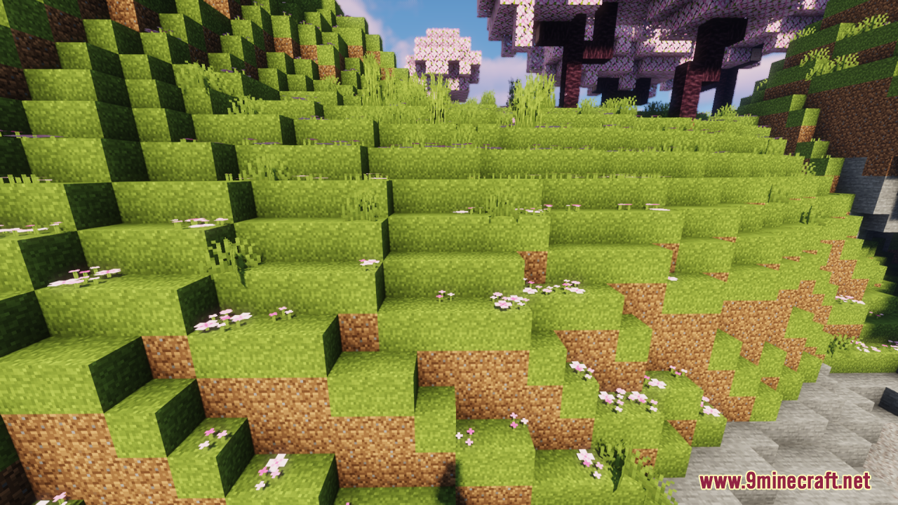 A lush green hillside with connected grass textures and small pink flowers