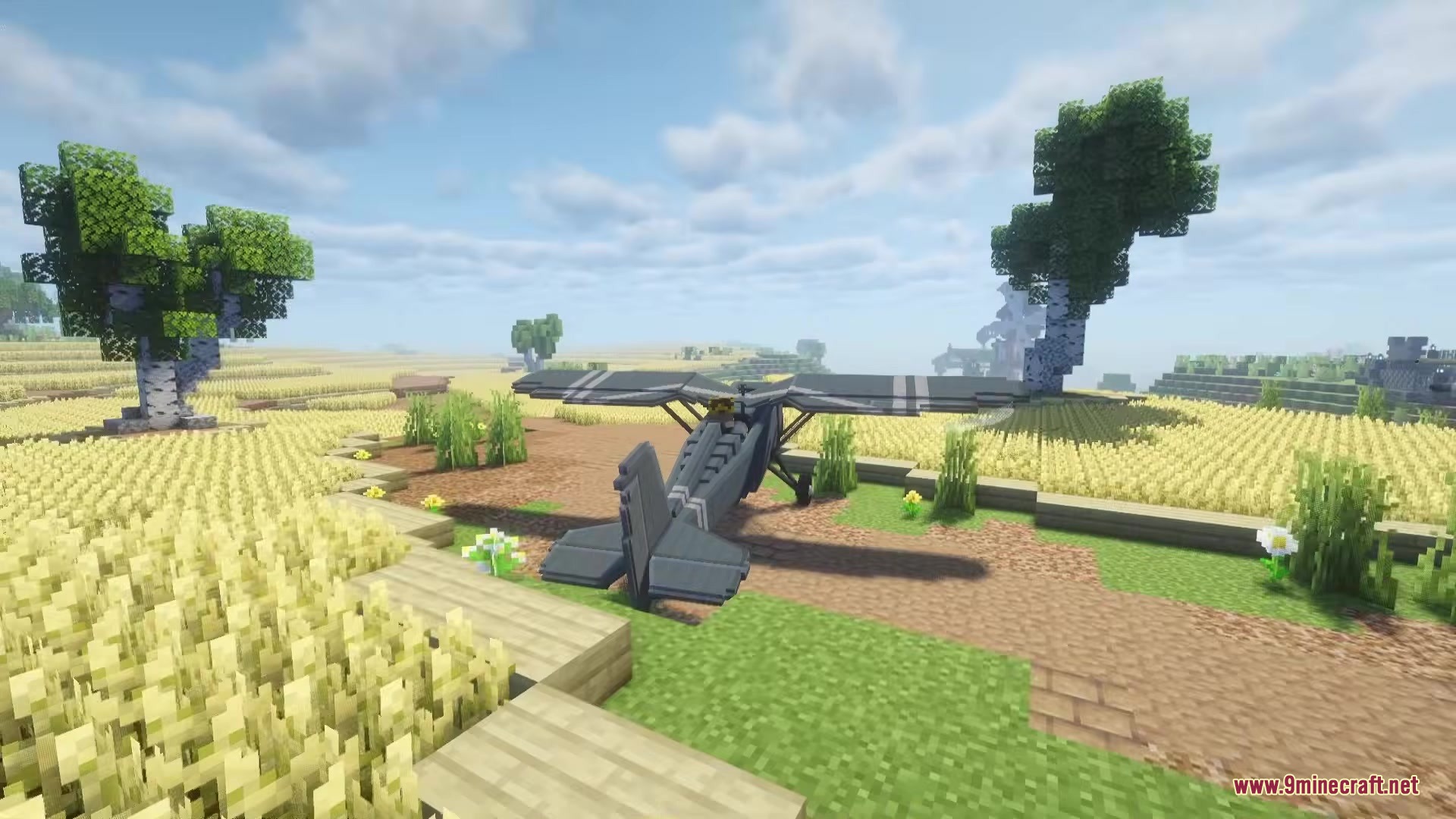 A grey airplane sits on a dirt path in a blocky wheat field