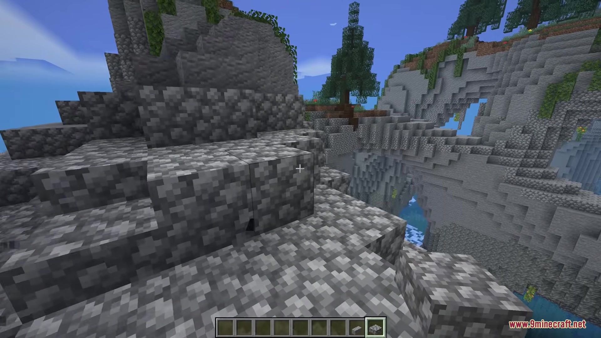 A player stands on a rocky mountain looking at placed cobblestone blocks