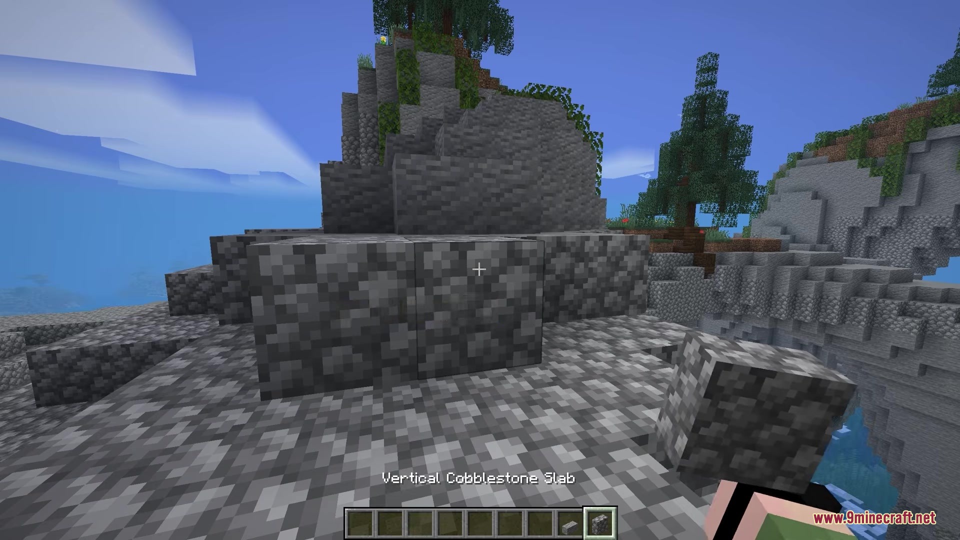 The player holds a vertical cobblestone slab in a rocky mountain biome