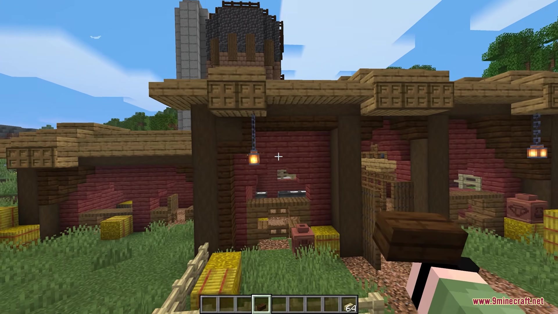 A player holds a dark oak block in front of a wooden barn