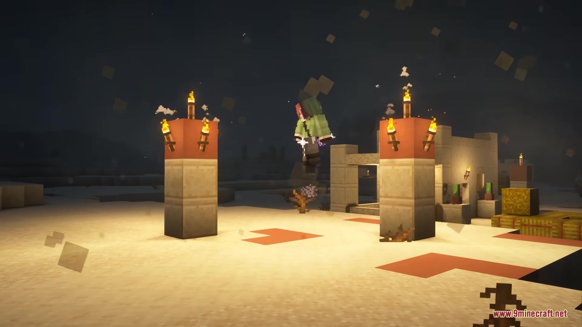 A player in a green suit levitates above a desert village at night