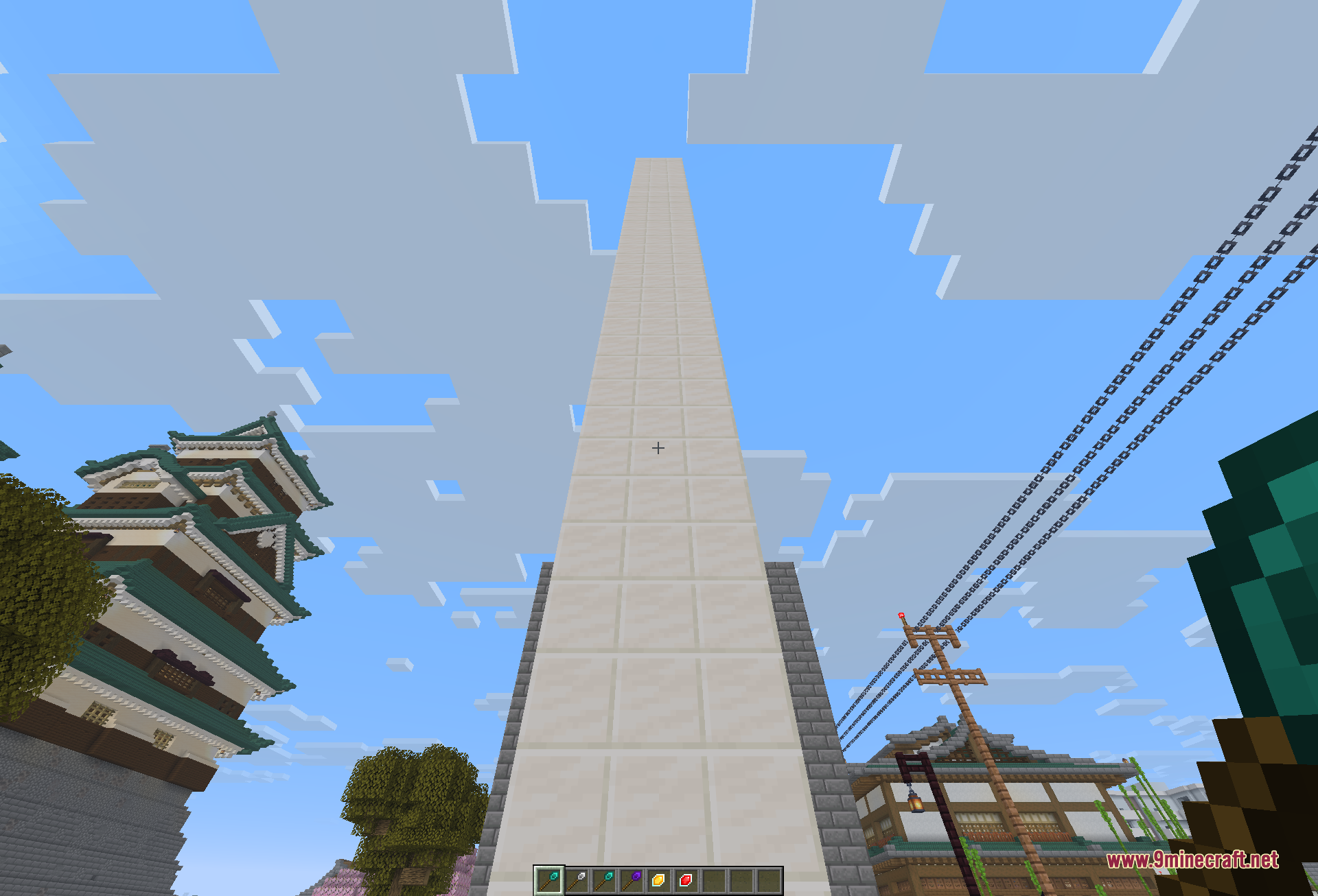 Looking straight up a towering white pillar that was extended high into the sky in a single wand action, framed by pagoda rooftops, power poles, and overhead wires