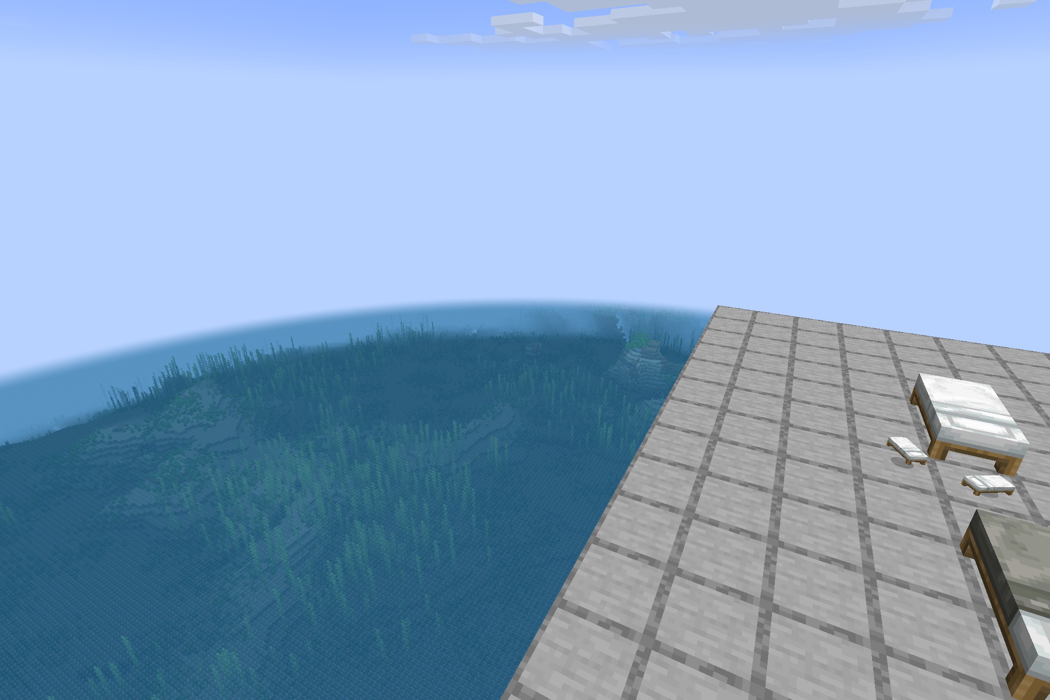 Beds with blankets on a stone platform overlooking a vast blue ocean