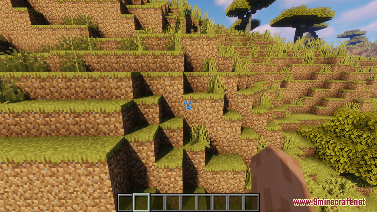 A blue Creeper face crosshair is shown over a grassy dirt hill
