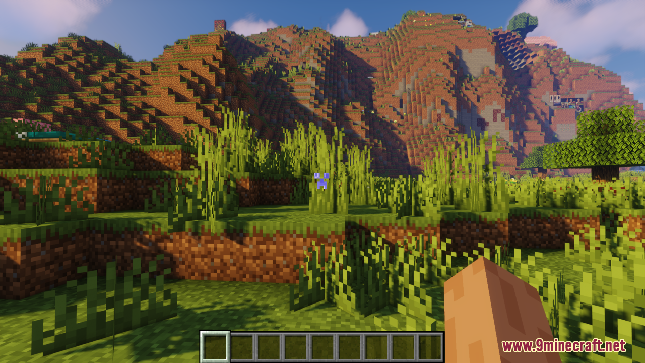 A lush green landscape with hills and a blue Creeper face crosshair