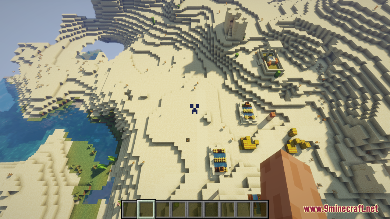 A blue creeper face crosshair shown over a desert biome from above