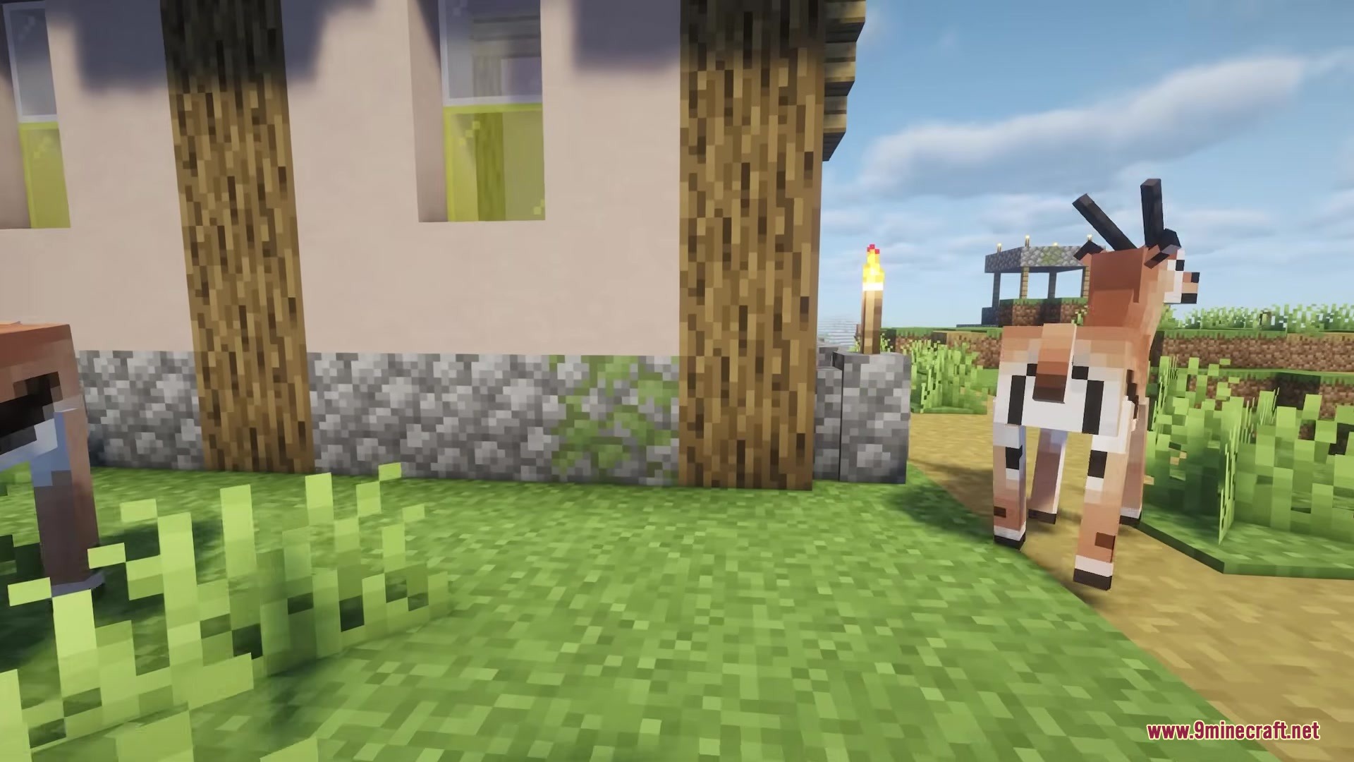 Cube Animals Mod Screenshot 5 A gazelle stands near a village house with cobblestone walls in Minecraft