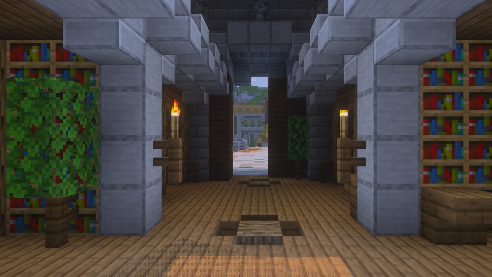 Interior view of a building with wooden floors stone pillars bookshelves and torches